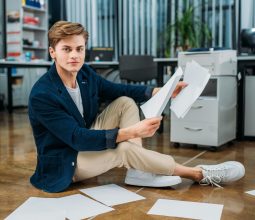 handsome young businessman sitting on floor and doing paperwork